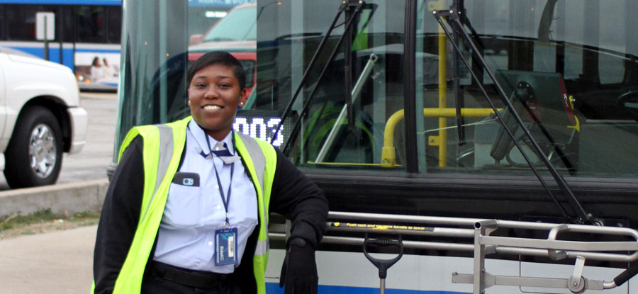 Bus operator in front of bus, smiling and ready to work.